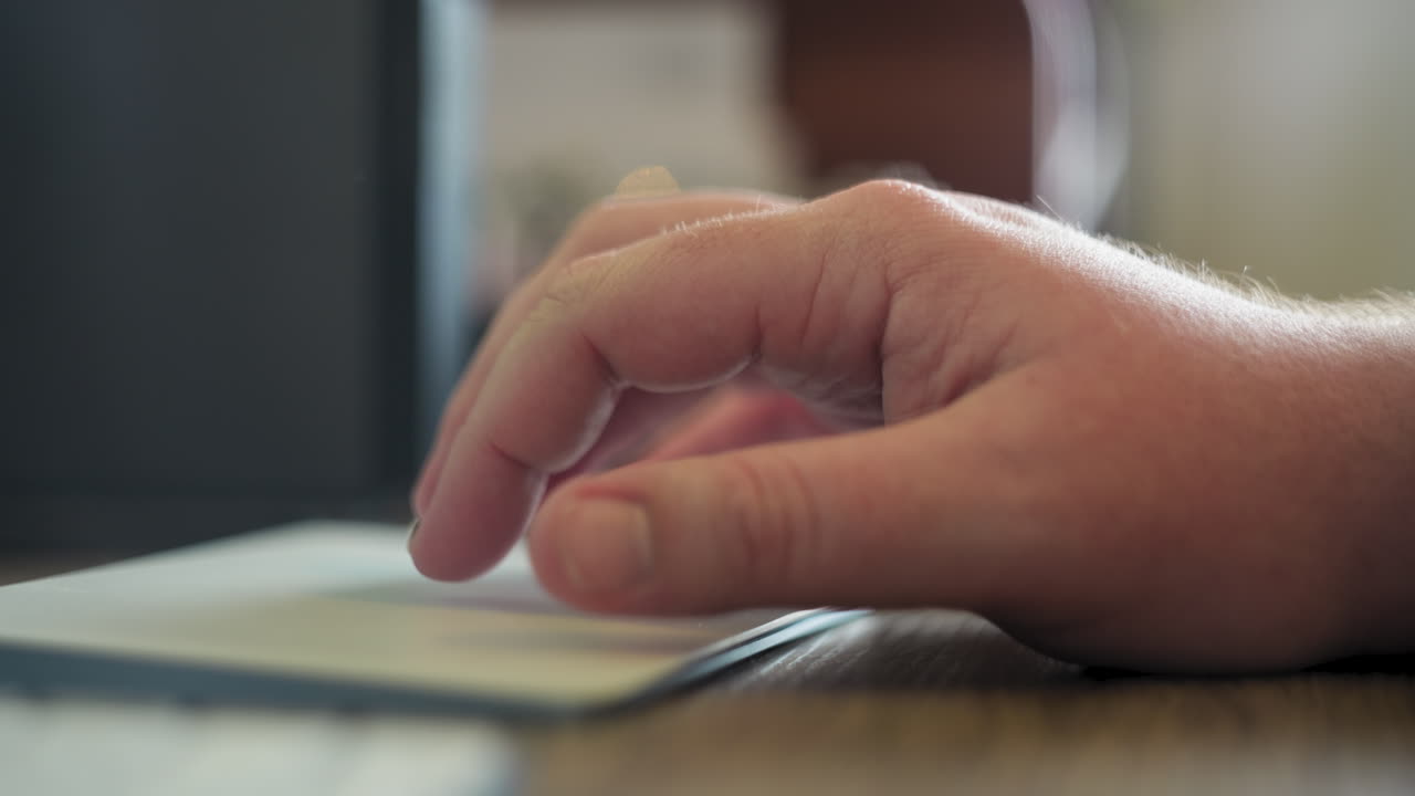 A caucasian man's hand clicking and swiping on a digital trackpad in his home office