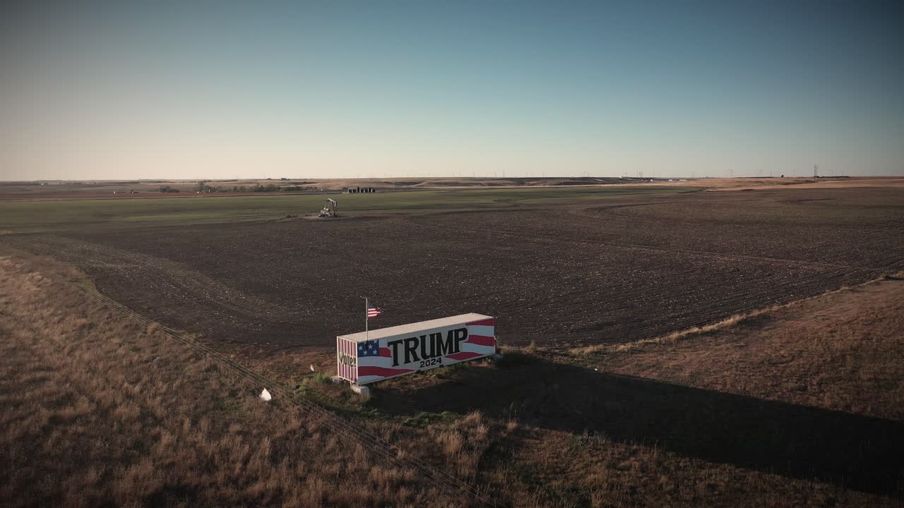 video oscuro y sombrío de un dron del propietario de tierras agrícolas partidario de donald trump con un cartel gigante de la campaña trump 2024 que alienta a la gente a votar por el presidente republicano