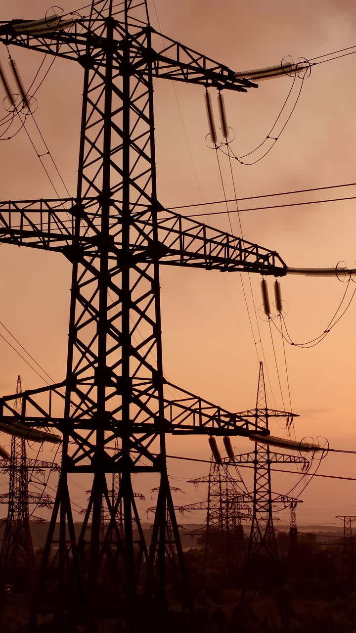Electricity tower with wires at sunset. Tall pylon carries wires that transport electric power from generating stations to electrical substations against the evening sky. Vertical video
