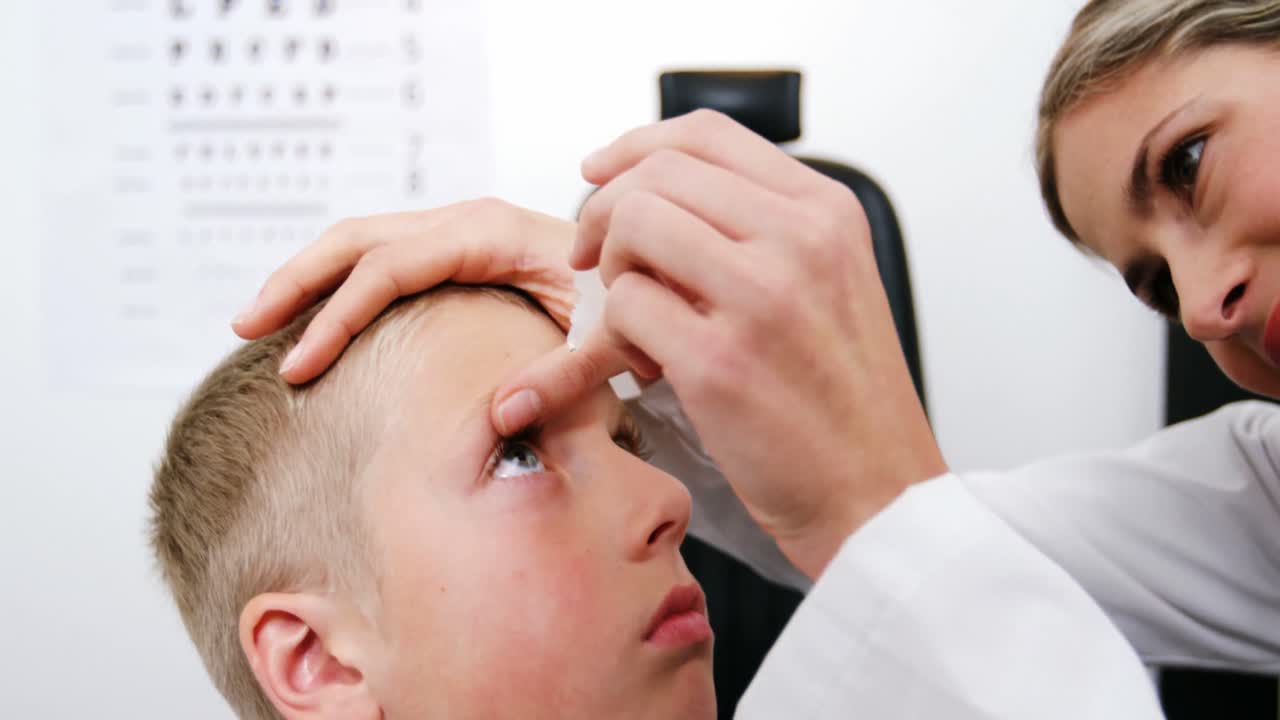 una optometra que pone gotas oculares en los ojos de un paciente joven