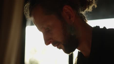close-up of a pensive man backlit by sunlight indoors