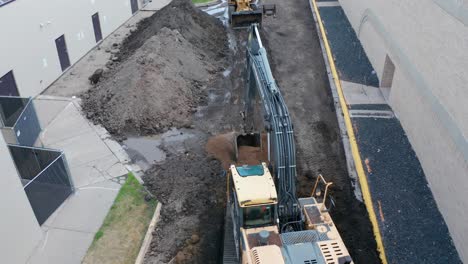 Aerial,-excavator-digging-soil-at-a-small-construction-site-to-rebuild-parking-lot-road