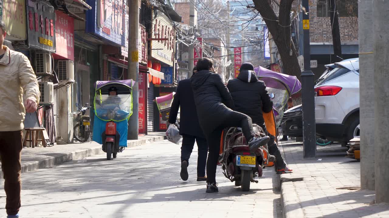 lively urban street features scooters, pedestrians walking, and local shops visible in the background on a clear sunny day in Xian china
