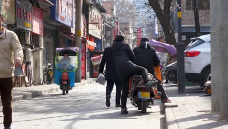 lively urban street features scooters, pedestrians walking, and local shops visible in the background on a clear sunny day in xian china