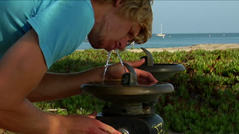A man sips water at a drink fountain