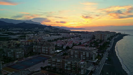 Yellow-sunset-over-small-town-and-sea-in-Spain,-aerial-view