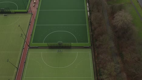 aerial view looking over multiple green sport fields with white dugouts next to an recreational nature area