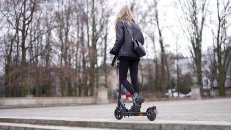 woman riding an electric scooter in a city park