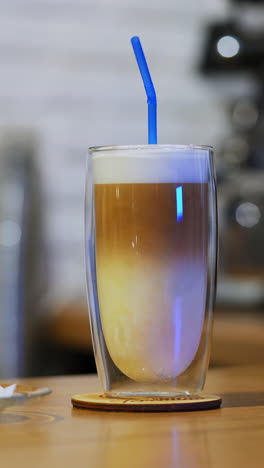serving beverage. tasty dessert on the table. woman puts straw into a glass of fresh drink and some sweet on a plate. close-up. vertical video