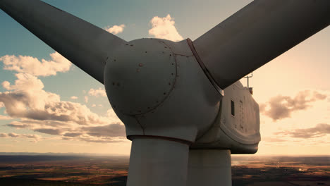 aerial circling wind turbine motionless during beautiful orange sunset. close up showing nacelle