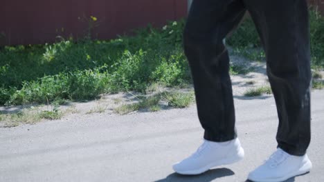 young man walking with guitar on street near forest