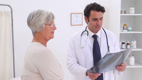 médico sosteniendo una radiografía del pecho y da un apretón de mano a un paciente
