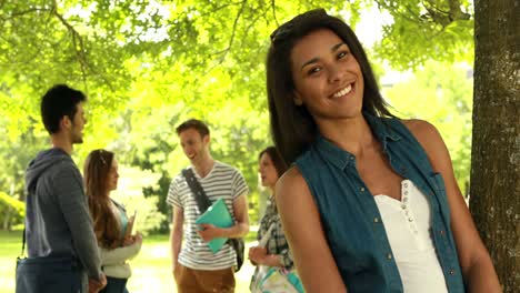 estudiante feliz posando y amigos hablando detrás de ella