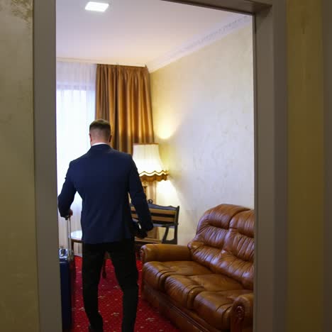 man comes into the hotel room. businessman with a suitcase entering the room. journey for business. back view