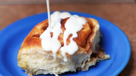 drizzling icing on a homemade cinnamon roll - isolated close up