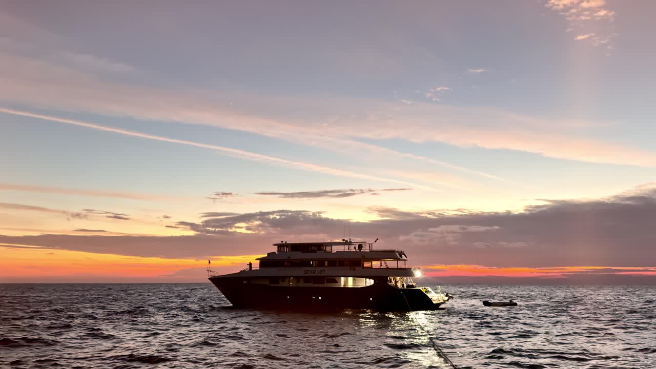 Solnedgångshorisont Röda Havet dyksafaribåt lyxyacht under gyllene timmen under mjuka pastellhimlar, låg vinkel från vattennivå under en lugn sommarkväll i Egypten med stilla vågor och livfulla nyanser.