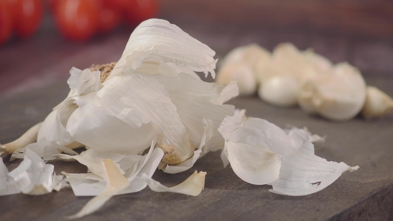 Bulbo d'aglio fresco e spicchi su un tagliere di legno