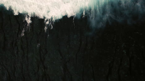 aerial birds eye view of dramatic dark moody ocean water with white foaming waves breaking