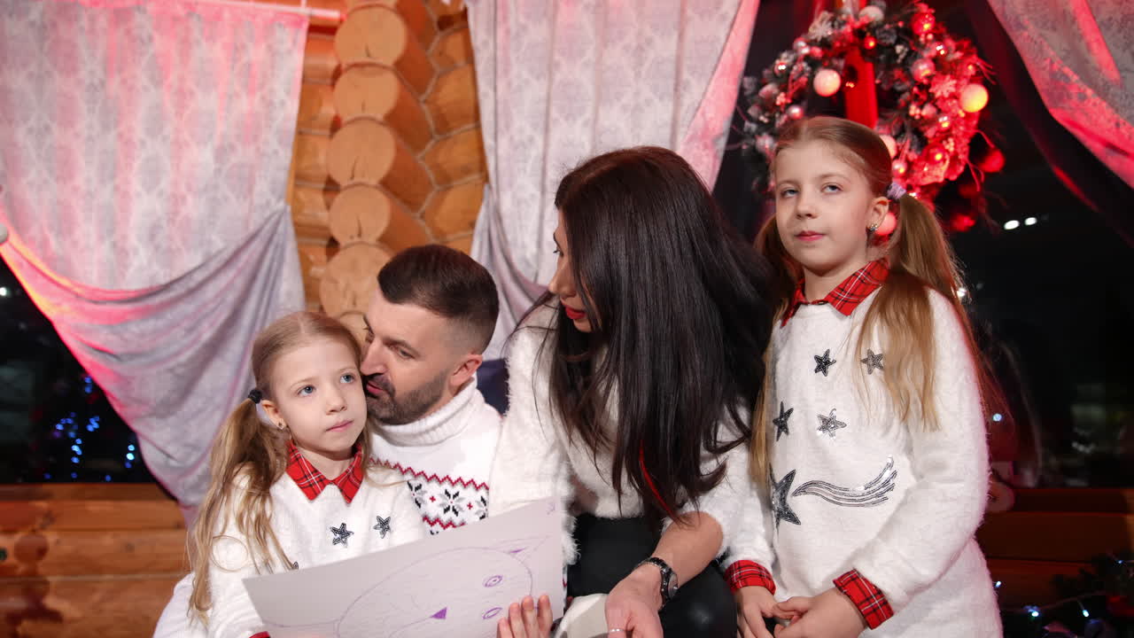 Father and mother looking at handmade pictures of their children while spending time at home togehter. Family waiting for the New Year