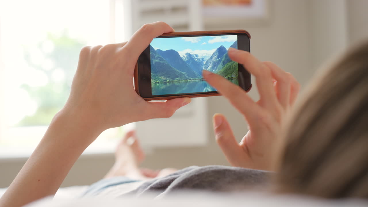 mujer mirando un teléfono con una imagen de la naturaleza