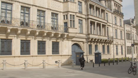 Tilt-down-from-chambre-des-députés-to-people-walking-over-street-in-downtown-luxembourg