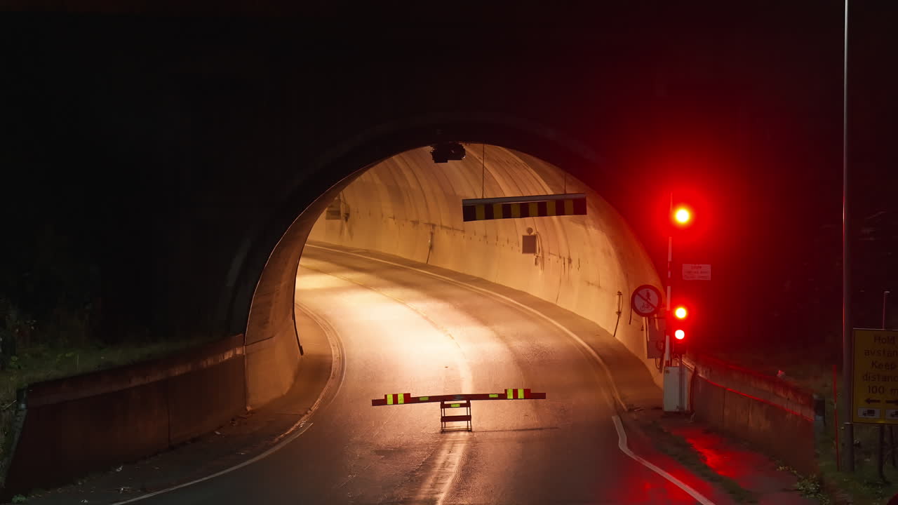 노르웨이 에서 야간 에 도로 터널 입구 에 들어갈 수 있는 장벽 이 없고 빨간색 교통등 이  ⁇ 박이는 것