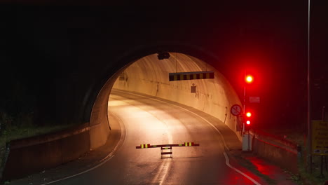 no entry barrier and red traffic lights flashing at the entrance of road tunnel at night in norway