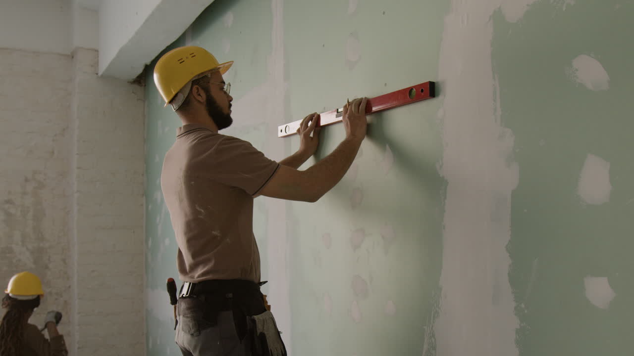 Construction workers renovating a wall with a level