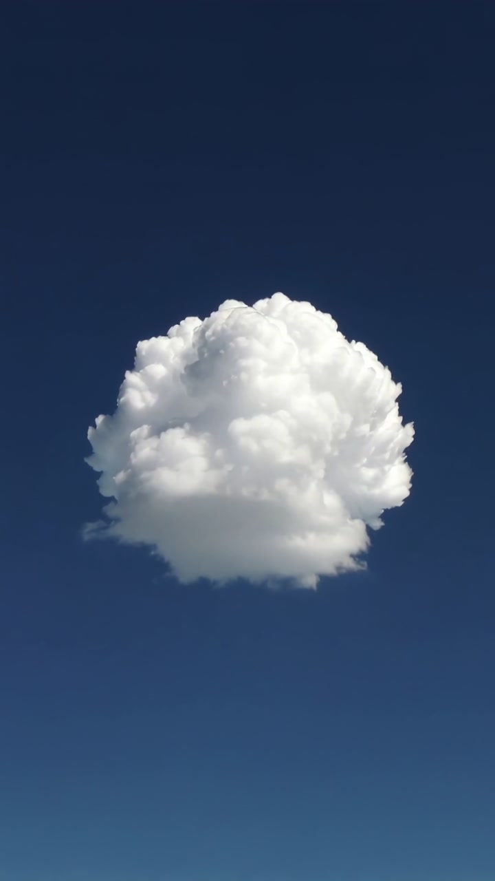 Vertical video: Growing cumulus cloud forming in deep blue sky, sun warming air fueling growth