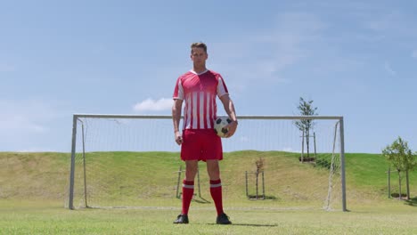 jugador de fútbol de pie con la pelota en el campo