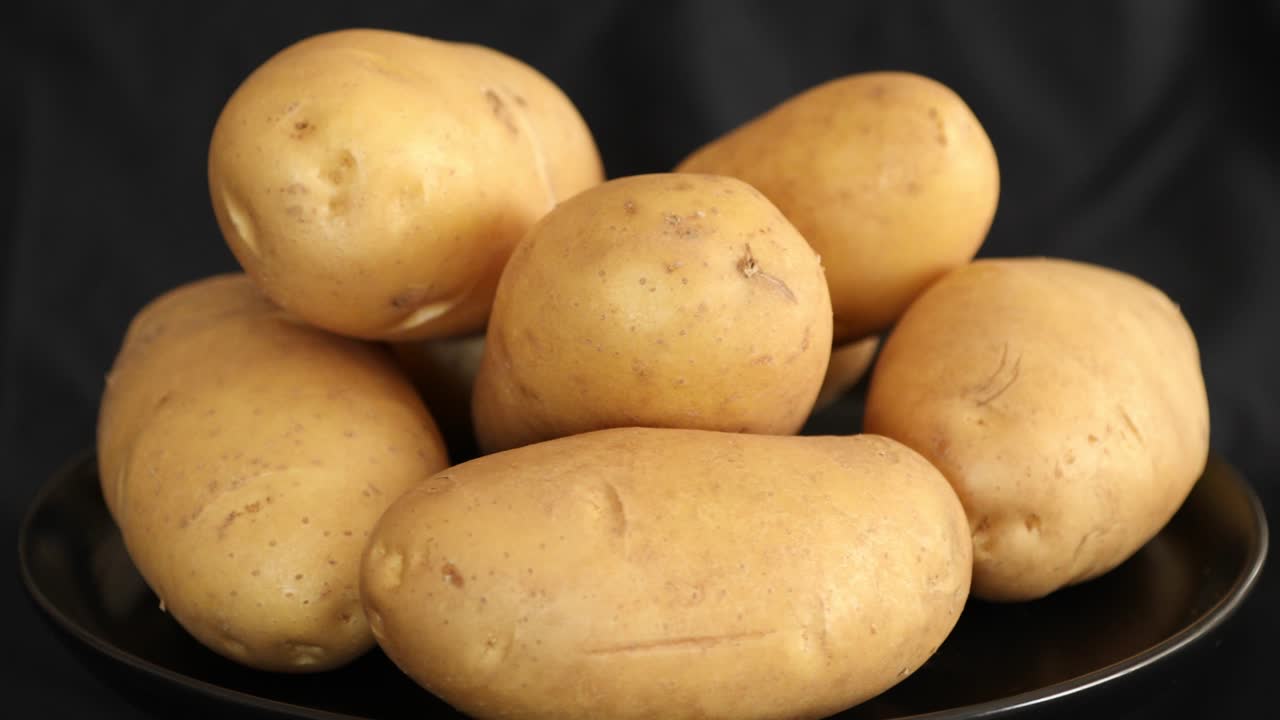 patatas crudas que giran y giran aisladas sobre un fondo negro 7