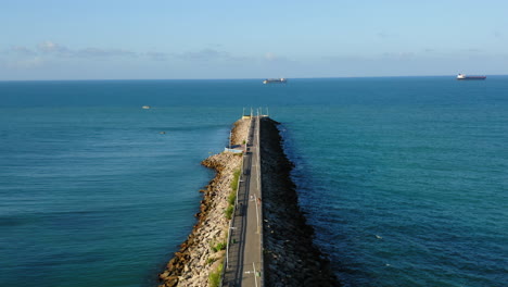 Vista-Aérea-De-La-Pasarela-Con-Gente-Caminando,-El-Mar-Y-Dos-Barcos-En-El-Fondo,-Fortaleza,-Ceará,-Brasil