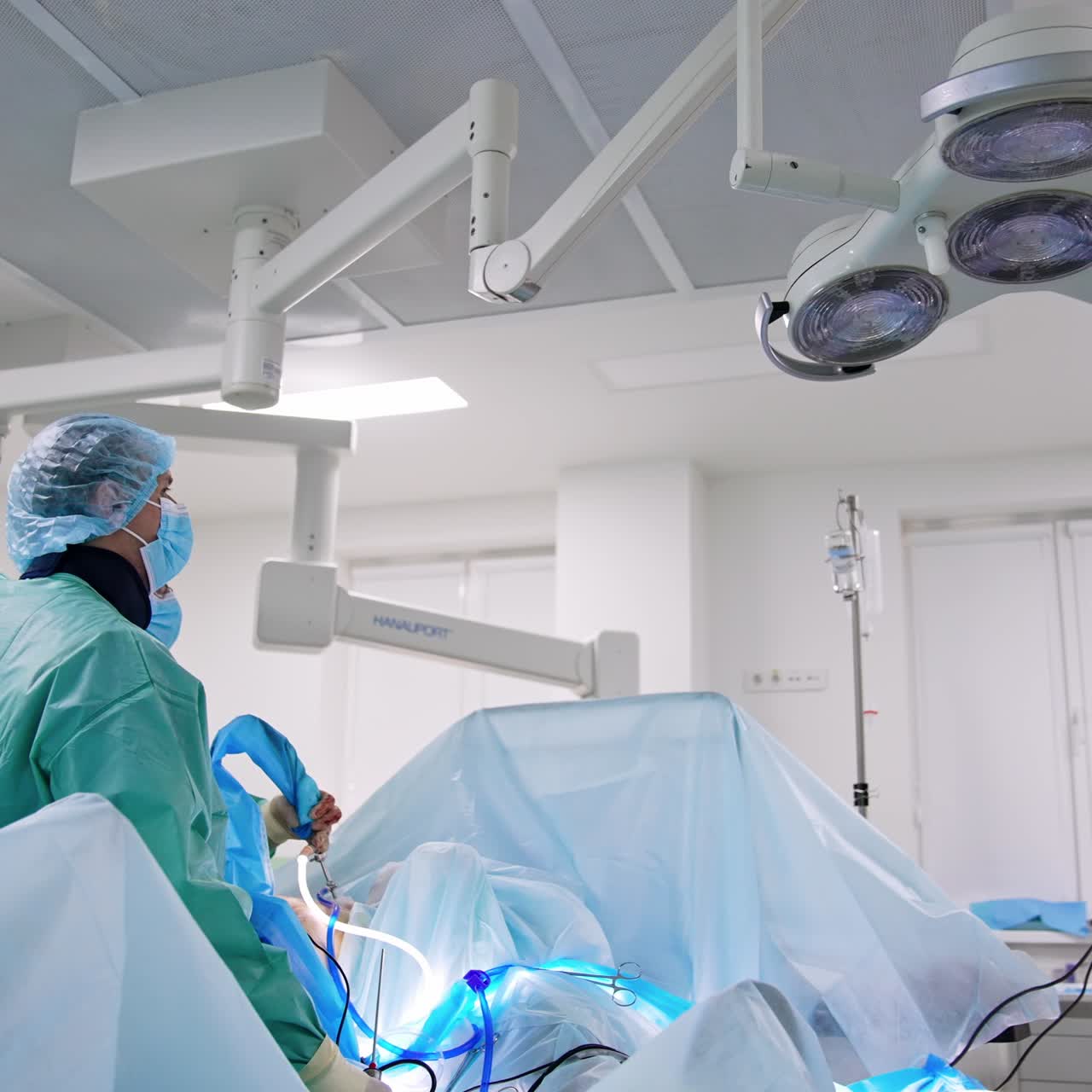 Cirujanos profesionales atienden al paciente en el quirófano. El cirujano principal utiliza una herramienta laparoscópica. Ambos médicos están concentrados en el monitor.