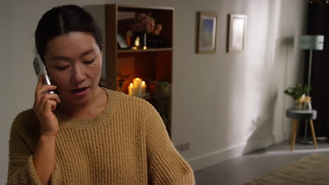 close up of smiling woman in lounge at home talking on mobile phone