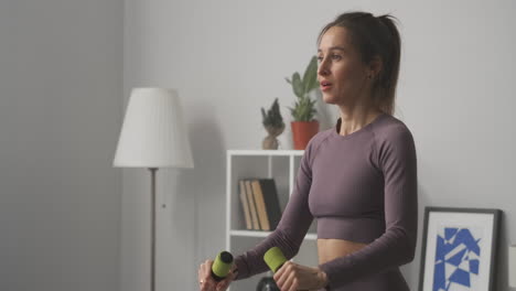 Una-Mujer-Deportiva-Sexy-Con-Cola-De-Caballo-Está-Entrenando-Con-Pesas-En-Un-Cuerpo-Femenino-Plano,-Delgado-Y-Musculoso,-Manteniéndose-En-Forma-Y-Perdiendo-Peso,-Bienestar-Y-Fitness