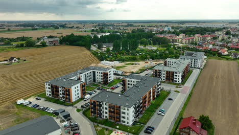 aerial view of a residential complex with several apartment buildings near agricultural fields and a small town. the scene captures the transition from rural to urban development - lubawa