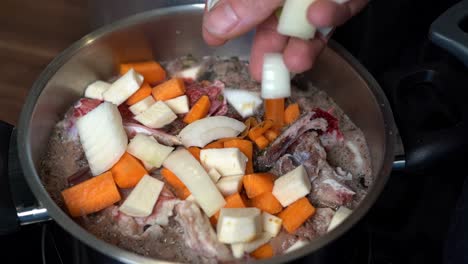 fresh onions being added to pot of homemade bone broth simmering on stove