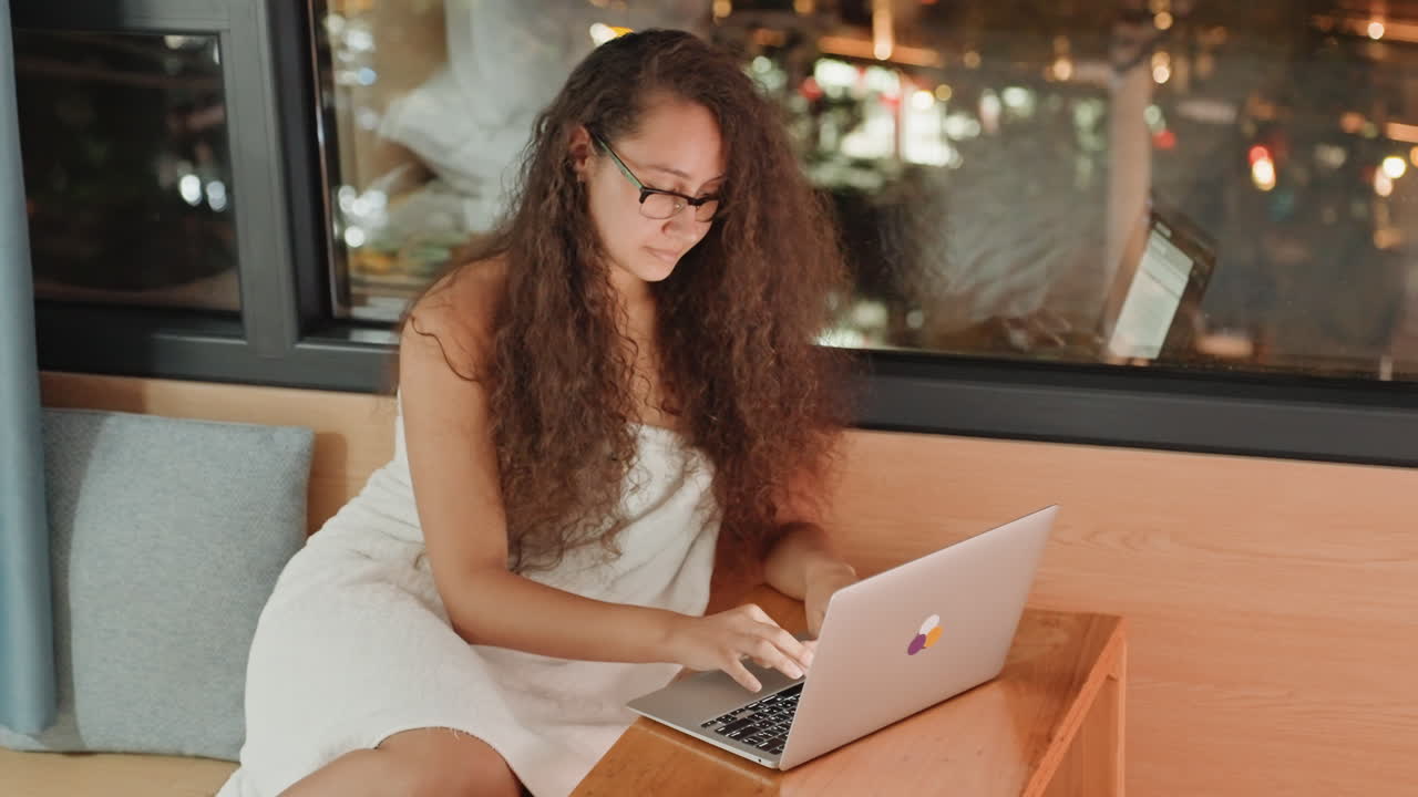 Female traveler working. Guest preparing travel arrangements. Woman organizing trip plans from hotel room. Female guest designing itinerary while overlooking cityscape through window
