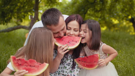 family enjoying a watermelon picnic in the park