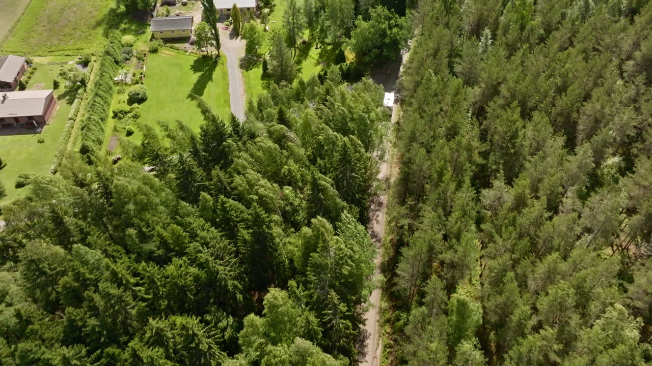 Aerial view of a RV driving in middle of detached forest homes, summer day