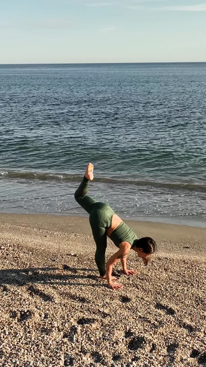 Active female in sportswear practicing yoga on beach