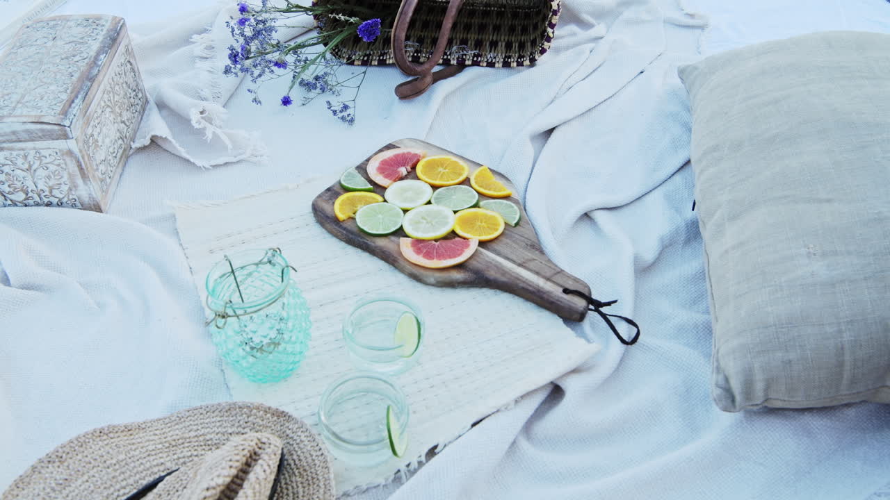 Putting freshly sliced citrus fruits on a small wooden chopping board on a picnic blanket - close up