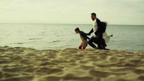 Playful-family-running-beach-sand.-Young-people-having-happy-time-at-sea-shore.