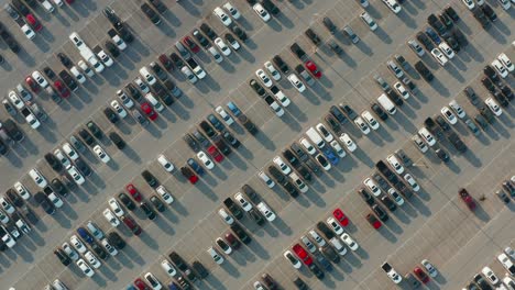 aerial top down orbit of parking lot with new and used cars, trucks, suvs