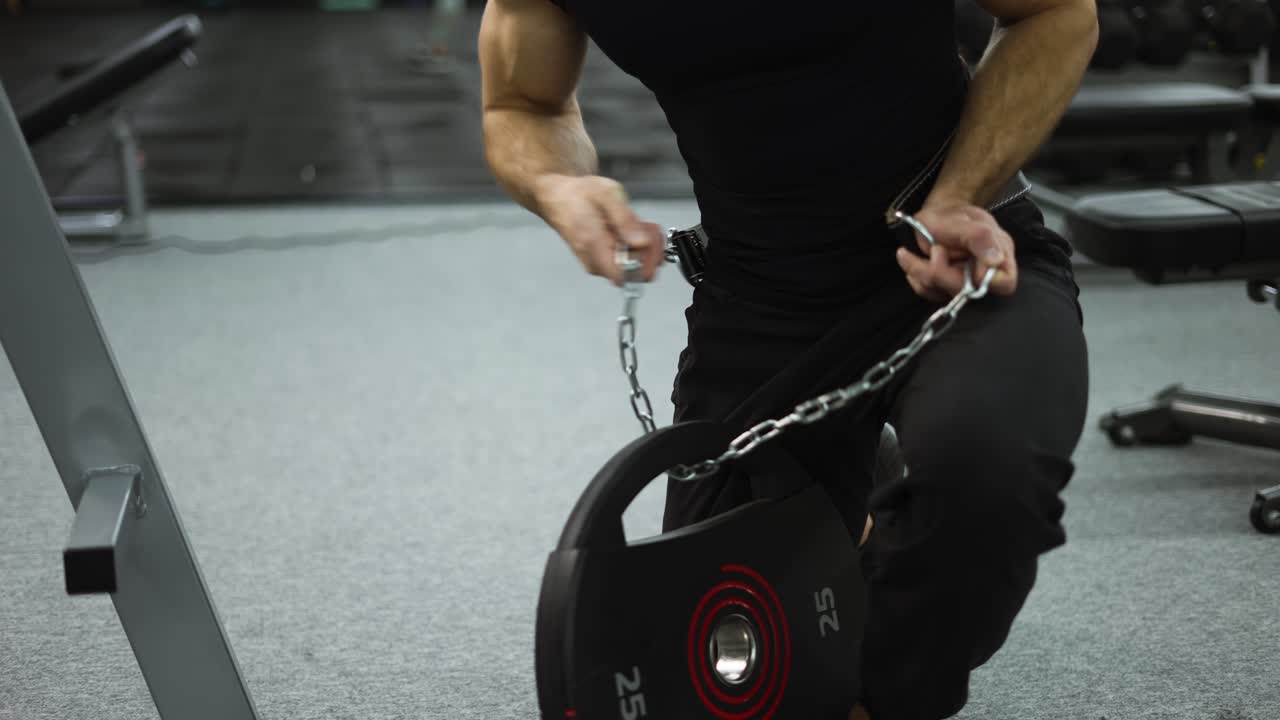 강한 스포츠맨은 손에 강철 체인과 웨이트리프팅 벨트를 들고 체육관에서 열심히 운동을 합니다.