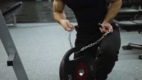 strong sportsman holding in hands steel chain and weightlifting belt goes to hard workout at gym