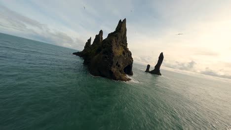 volando con un dron fpv sobre las pilas marinas de reynisdrangar en el océano atlántico cerca de vík, islandia