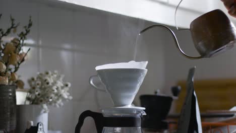 il bollitore di rame versa l'acqua attraverso il filtro del caffè v60 nel server di vetro