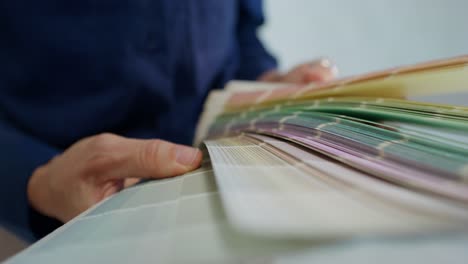 person selecting paint colors from a swatch book.