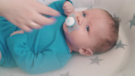 la mamá le da un chupete al hijo que llora en un cómodo capullo